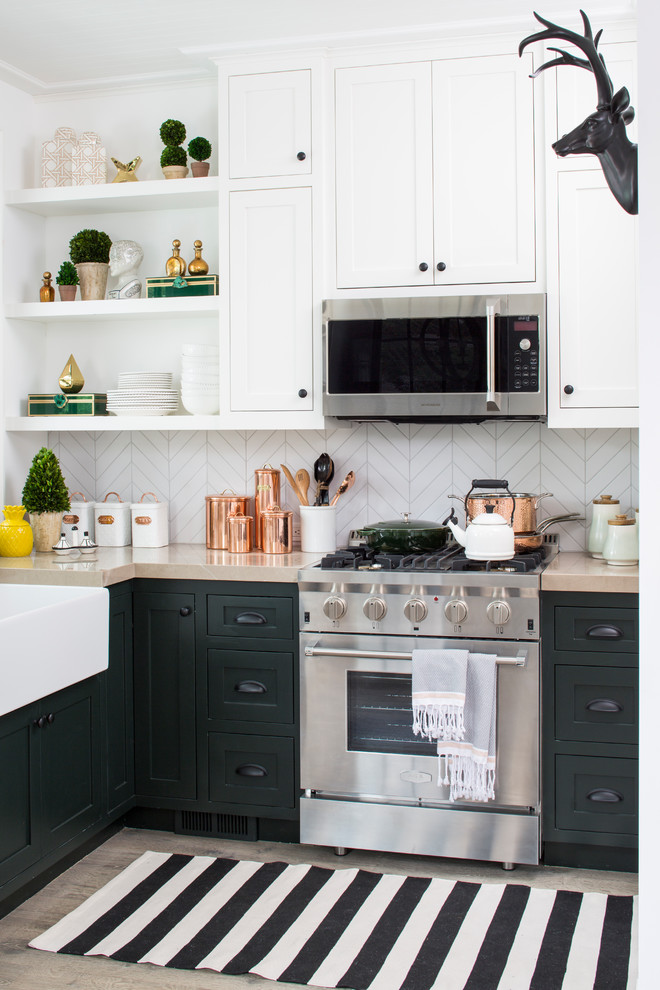 Mid-sized transitional l-shaped kitchen in Los Angeles with a farmhouse sink, shaker cabinets, green cabinets, white splashback, porcelain splashback, stainless steel appliances, light hardwood floors, no island and beige floor.