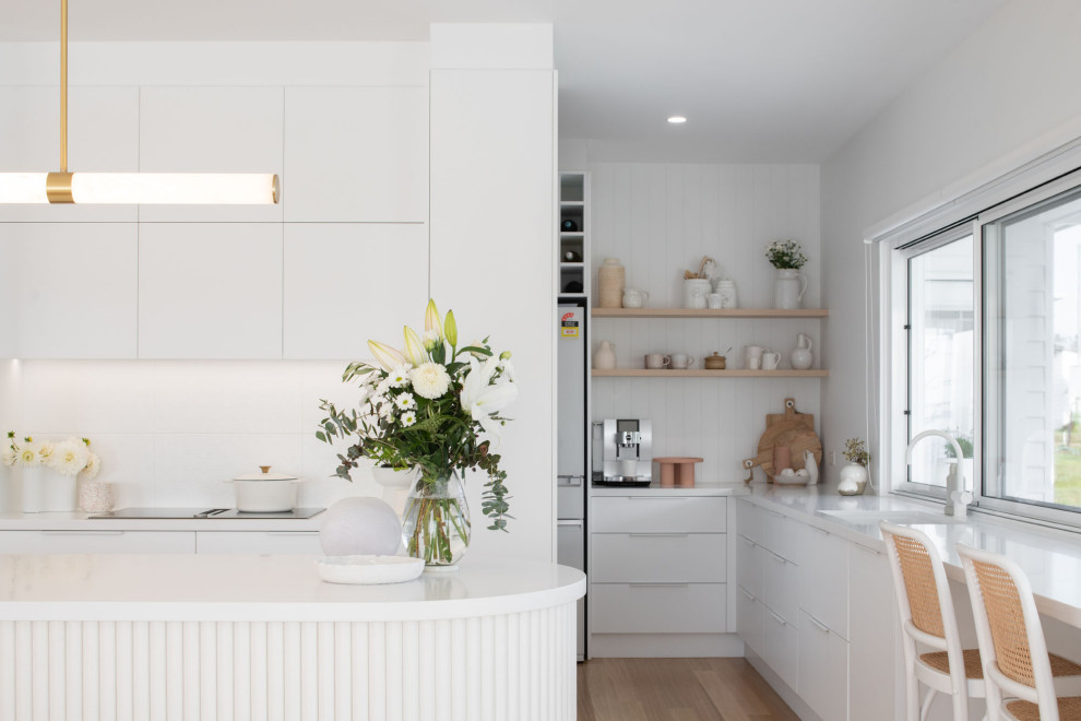 Inspiration for a country kitchen pantry in Hobart with an undermount sink, white cabinets, quartz benchtops, white splashback, ceramic splashback, white appliances, light hardwood floors, with island and white benchtop.