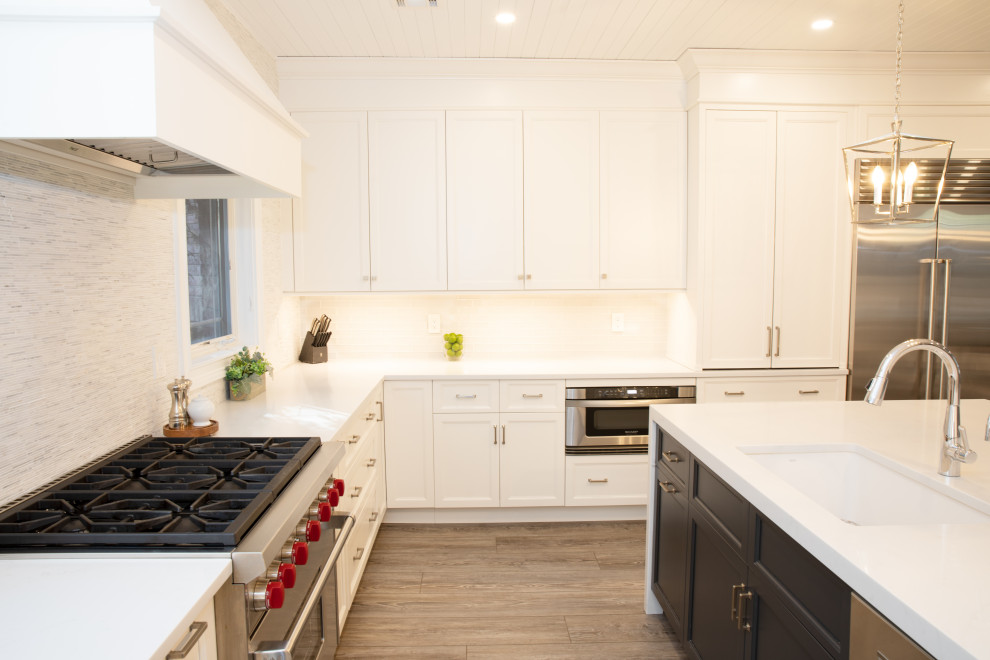 Large transitional u-shaped eat-in kitchen in New York with an undermount sink, shaker cabinets, white cabinets, quartz benchtops, multi-coloured splashback, marble splashback, stainless steel appliances, with island and white benchtop.
