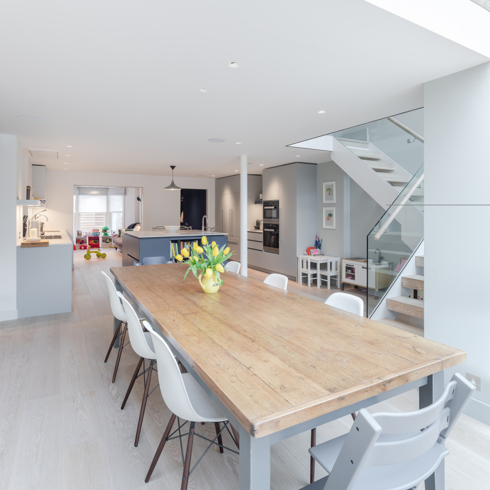 This is an example of a contemporary open plan kitchen in Other with flat-panel cabinets, grey cabinets and white benchtop.