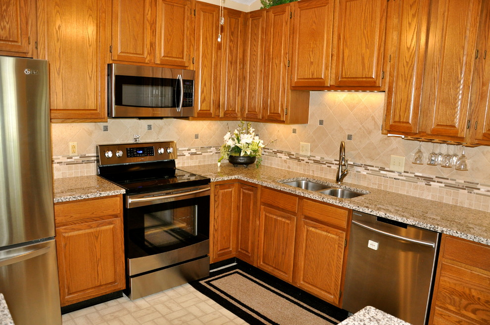 Inspiration for a small transitional u-shaped linoleum floor enclosed kitchen remodel in Cincinnati with an undermount sink, recessed-panel cabinets, medium tone wood cabinets, granite countertops, beige backsplash, stone tile backsplash, stainless steel appliances and orange walls