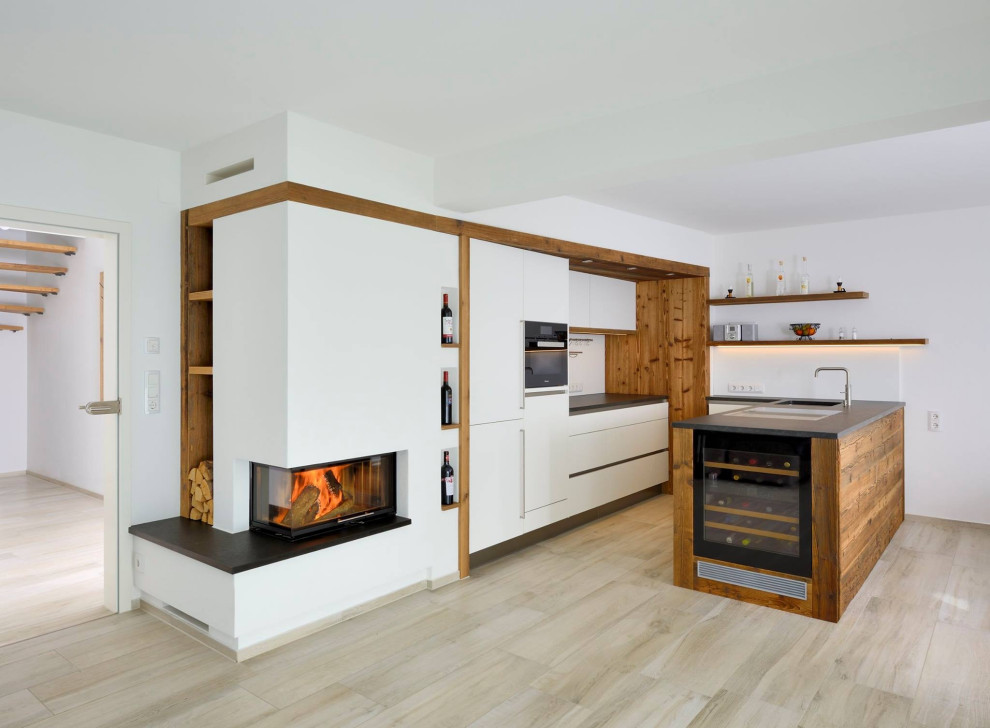 Mid-sized contemporary l-shaped kitchen in Munich with an undermount sink, flat-panel cabinets, white cabinets, panelled appliances, a peninsula, beige floor and black benchtop.