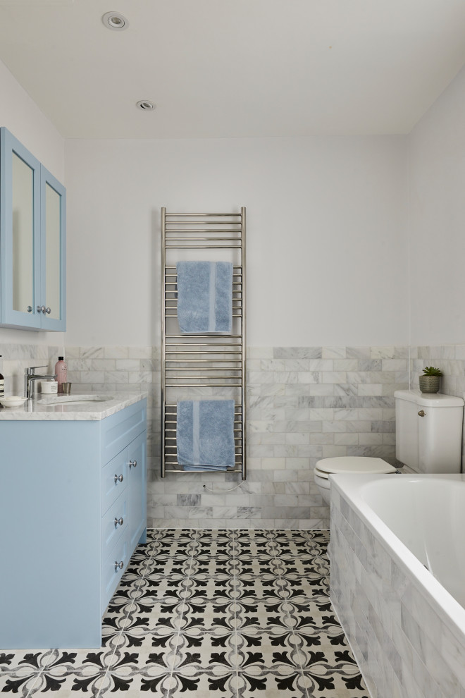 Großes Modernes Kinderbad mit blauen Schränken, Einbaubadewanne, offener Dusche, Wandtoilette mit Spülkasten, grauen Fliesen, integriertem Waschbecken, Marmor-Waschbecken/Waschtisch, Falttür-Duschabtrennung, Einzelwaschbecken und freistehendem Waschtisch in London