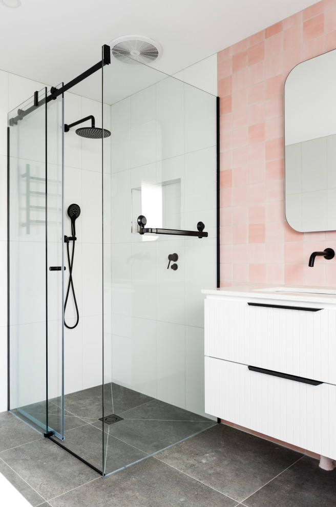 Стильный дизайн: большая главная ванная комната в современном стиле с фасадами с декоративным кантом, белыми фасадами, отдельно стоящей ванной, угловым душем, унитазом-моноблоком, розовой плиткой, керамогранитной плиткой, розовыми стенами, полом из керамогранита, врезной раковиной, столешницей из искусственного кварца, серым полом, душем с раздвижными дверями, белой столешницей, фартуком, тумбой под две раковины и подвесной тумбой - последний тренд