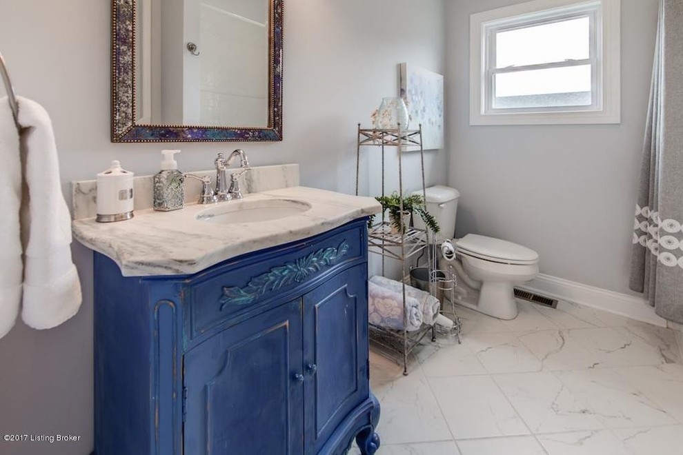 Country powder room in Louisville with furniture-like cabinets, distressed cabinets, gray tile, porcelain tile, grey walls, ceramic floors, an undermount sink, marble benchtops and grey floor.