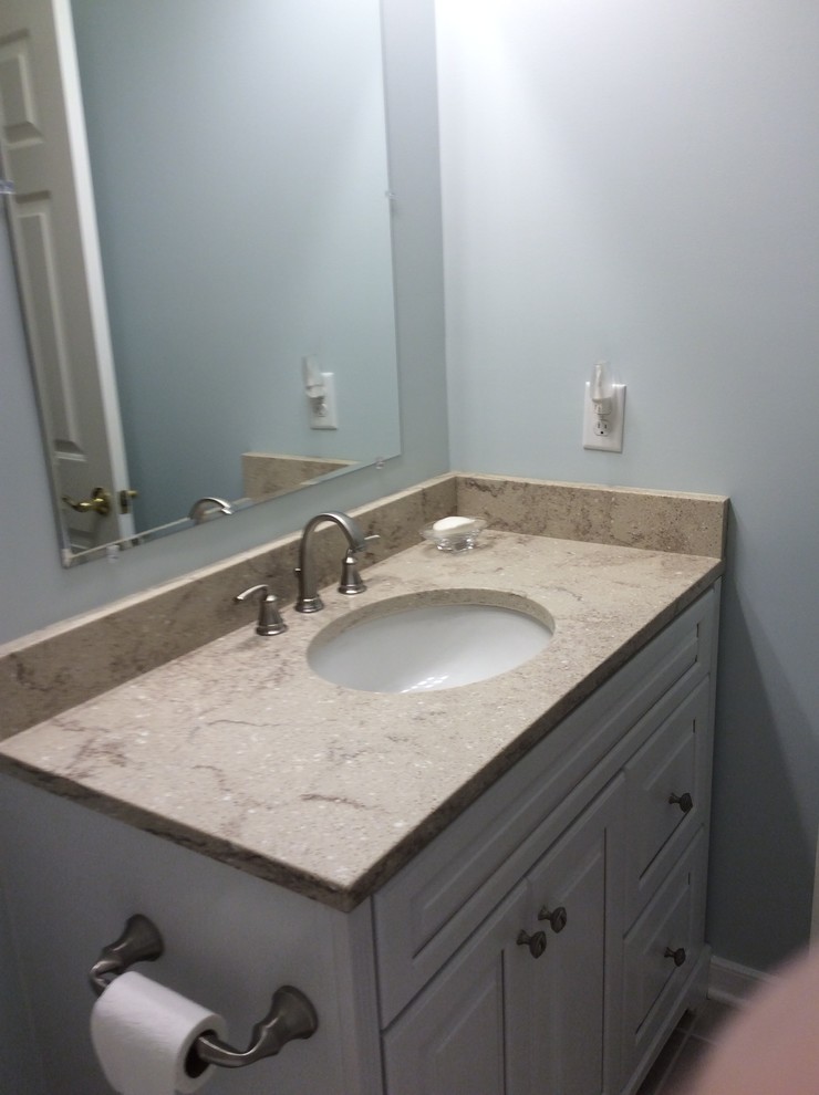 Alcove shower - mid-sized traditional 3/4 gray tile and porcelain tile porcelain tile alcove shower idea in Richmond with raised-panel cabinets, white cabinets, a two-piece toilet, blue walls, an undermount sink and quartz countertops