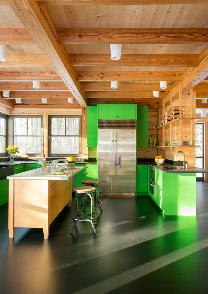 Photo of a country u-shaped eat-in kitchen in Boston with a farmhouse sink, flat-panel cabinets, green cabinets, brown splashback, timber splashback, stainless steel appliances, with island, black floor and black benchtop.