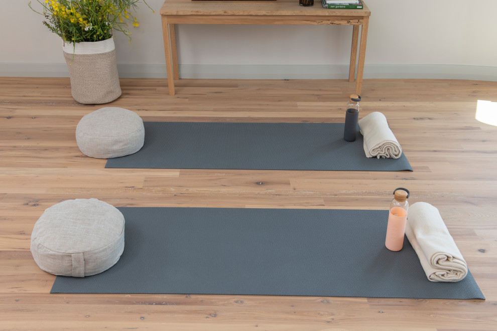Foto di un ampio studio yoga stile marinaro con pareti bianche, parquet chiaro, pavimento marrone e travi a vista