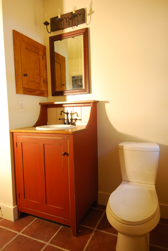 Photo of a country master bathroom in Other with furniture-like cabinets, red cabinets, an alcove shower, a one-piece toilet, red tile, terra-cotta tile, white walls, terra-cotta floors, a drop-in sink and wood benchtops.