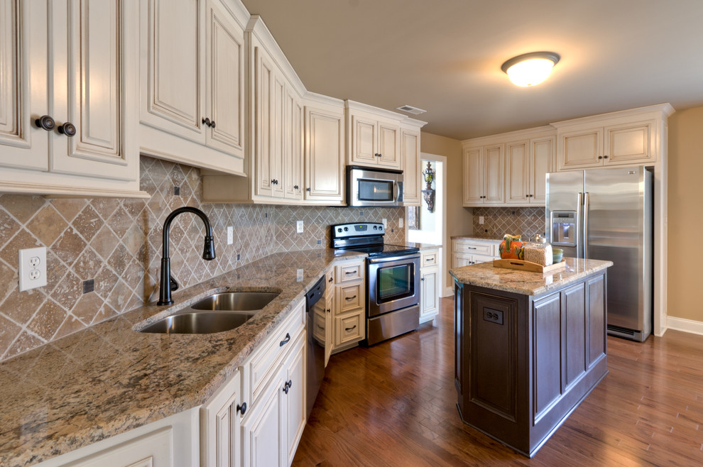 Kitchen - large ceramic tile kitchen idea with an undermount sink, raised-panel cabinets, distressed cabinets, granite countertops, ceramic backsplash, stainless steel appliances and an island
