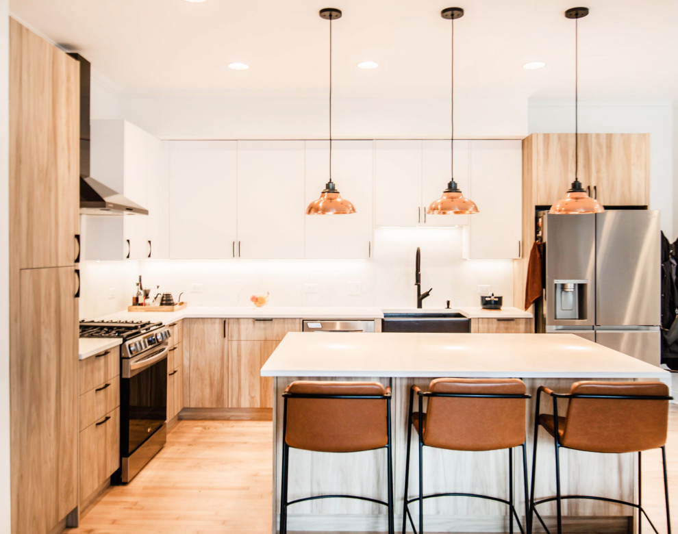 Inspiration for a contemporary l-shaped kitchen in Chicago with a farmhouse sink, flat-panel cabinets, light wood cabinets, white splashback, stainless steel appliances, light hardwood floors, with island and white benchtop.