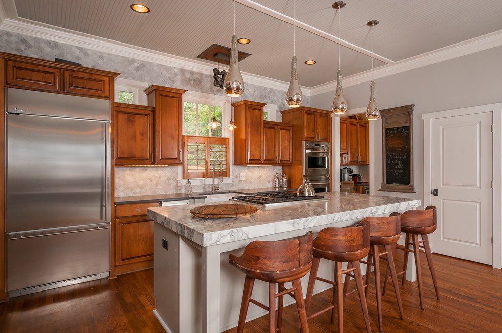 Traditional galley kitchen in Atlanta with a farmhouse sink, raised-panel cabinets, medium wood cabinets, grey splashback, stainless steel appliances, medium hardwood floors and with island.