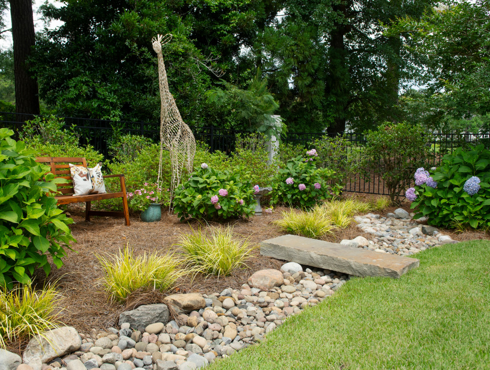 Eclectic backyard garden in Other with river rock.