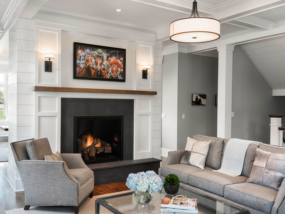 Photo of a large transitional formal open concept living room with grey walls, medium hardwood floors, a standard fireplace, no tv, brown floor, a stone fireplace surround and planked wall panelling.