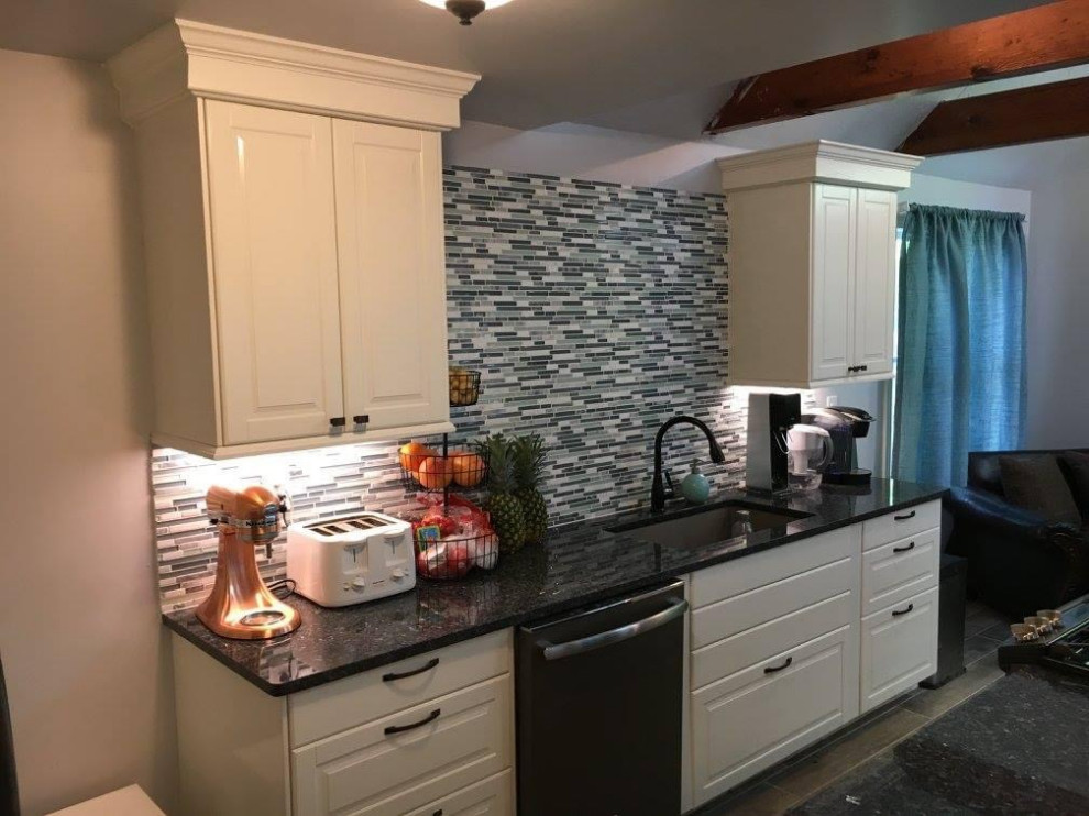 This is an example of a large beach style eat-in kitchen in Los Angeles with an undermount sink, raised-panel cabinets, white cabinets, granite benchtops, blue splashback, mosaic tile splashback, stainless steel appliances, ceramic floors, with island, grey floor, blue benchtop and vaulted.