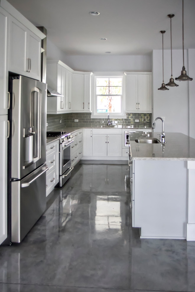 Inspiration for a mid-sized modern l-shaped eat-in kitchen in Jacksonville with with island, shaker cabinets, white cabinets, an undermount sink, granite benchtops, grey splashback, subway tile splashback, stainless steel appliances and concrete floors.