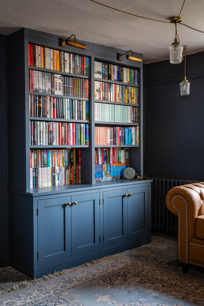 Modelo de biblioteca en casa tradicional de tamaño medio sin televisor con paredes azules, suelo de pizarra, estufa de leña, marco de chimenea de piedra y suelo gris