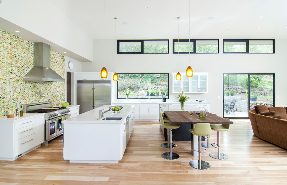 Photo of a contemporary open plan kitchen in San Francisco with stainless steel appliances, wood benchtops, green splashback, mosaic tile splashback, flat-panel cabinets, white cabinets and an undermount sink.