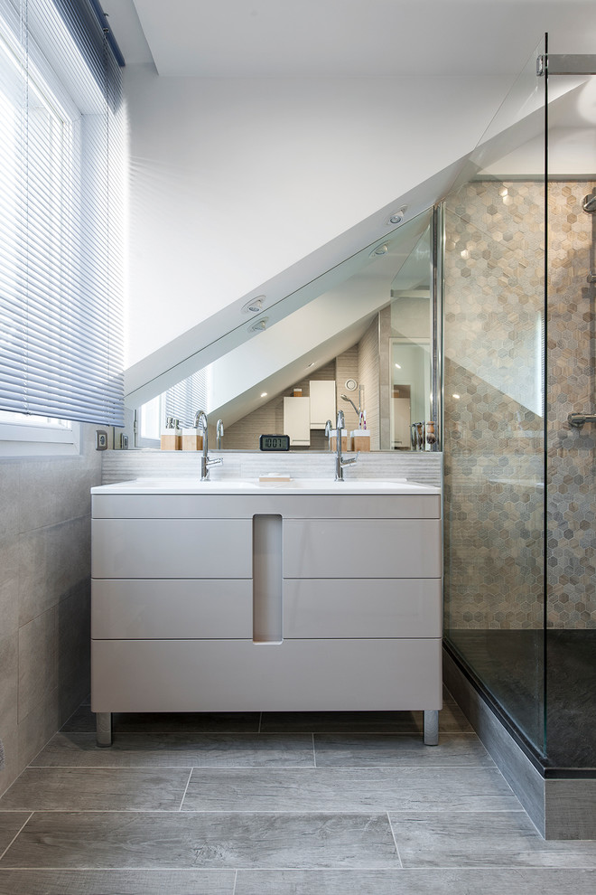 This is an example of a large contemporary master bathroom in Paris with a corner shower, a wall-mount toilet, beige tile, beige walls, grey floor and a sliding shower screen.