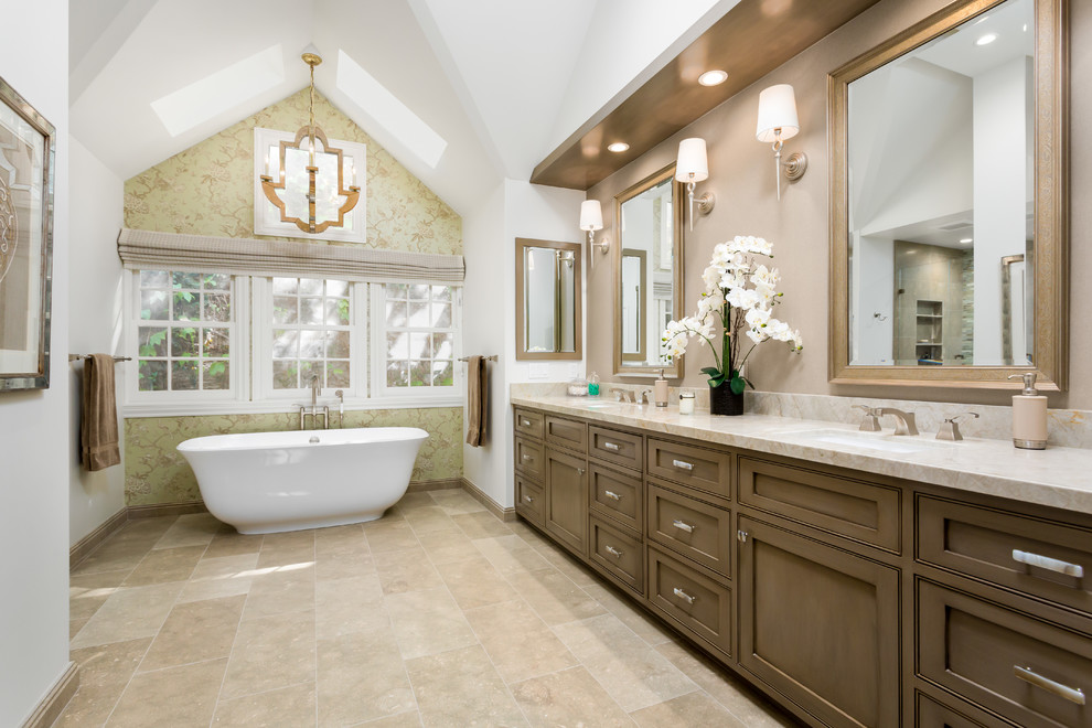 This is an example of a traditional master bathroom in Los Angeles with shaker cabinets, medium wood cabinets, a freestanding tub, white walls and marble benchtops.