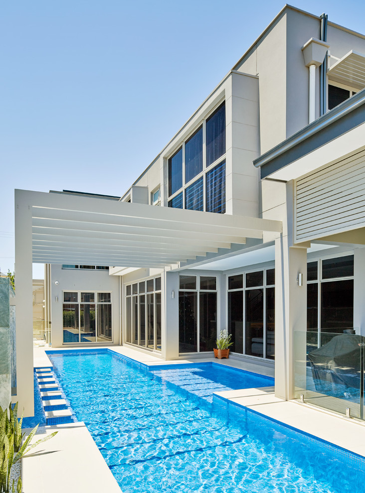 This is an example of a large contemporary backyard custom-shaped lap pool in Sydney with natural stone pavers.