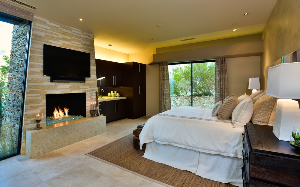 Design ideas for a large contemporary guest bedroom in Other with beige walls, travertine floors, a standard fireplace and a tile fireplace surround.