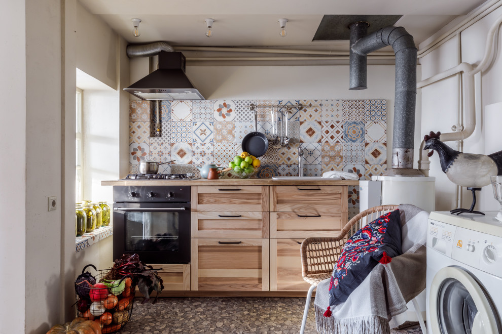 Photo of a small country single-wall kitchen in Other with a drop-in sink, shaker cabinets, beige cabinets, wood benchtops, multi-coloured splashback, mosaic tile splashback, no island, grey floor and beige benchtop.