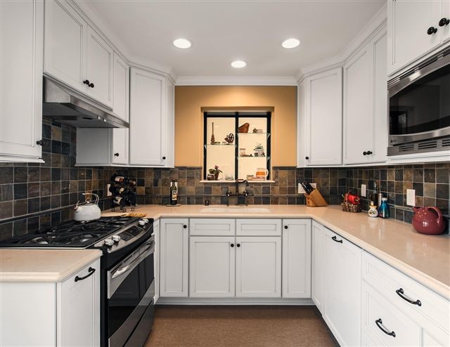 Design ideas for a small transitional u-shaped kitchen in Los Angeles with a double-bowl sink, recessed-panel cabinets, white cabinets, quartz benchtops, terra-cotta splashback, stainless steel appliances and linoleum floors.