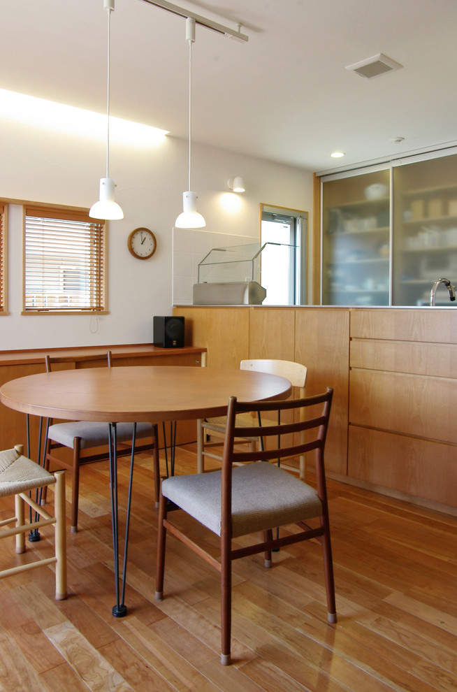 Photo of a mid-sized contemporary single-wall eat-in kitchen in Yokohama with glass-front cabinets, medium wood cabinets, stainless steel benchtops, white splashback, porcelain splashback, stainless steel appliances and with island.