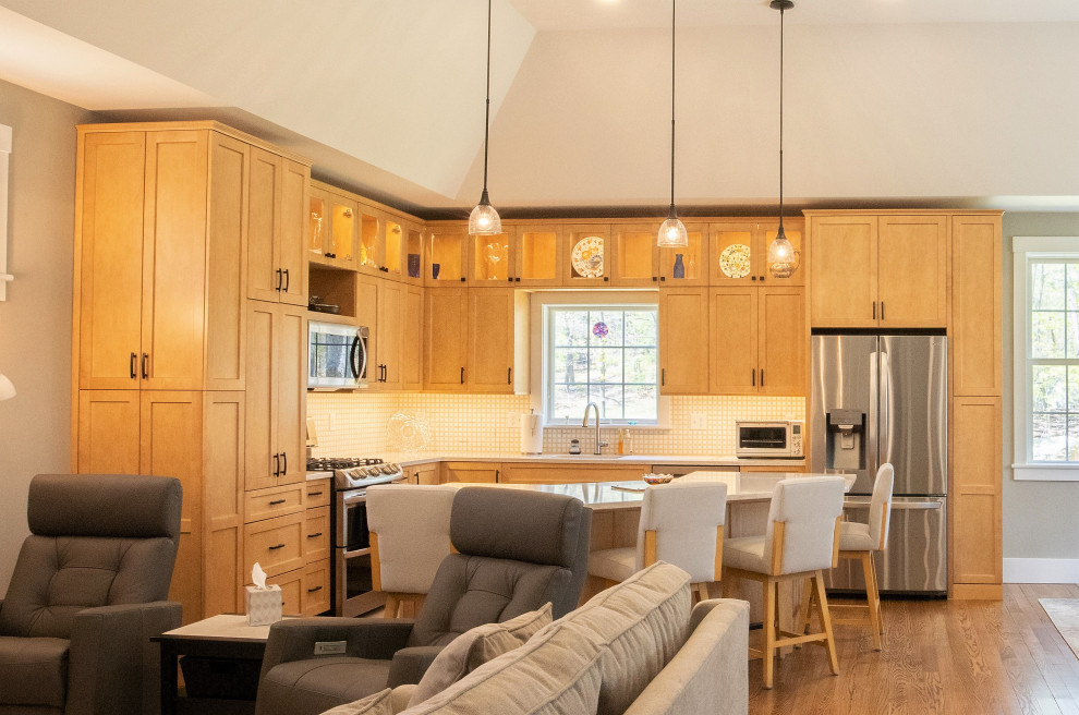 This is an example of a mid-sized contemporary l-shaped open plan kitchen in Boston with an undermount sink, shaker cabinets, light wood cabinets, quartz benchtops, yellow splashback, ceramic splashback, stainless steel appliances, medium hardwood floors, with island, brown floor, white benchtop and recessed.
