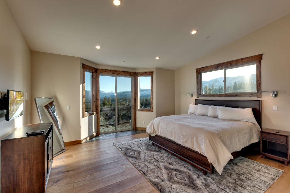 Inspiration for a large transitional master bedroom in Other with beige walls, light hardwood floors, a two-sided fireplace, a tile fireplace surround and vaulted.
