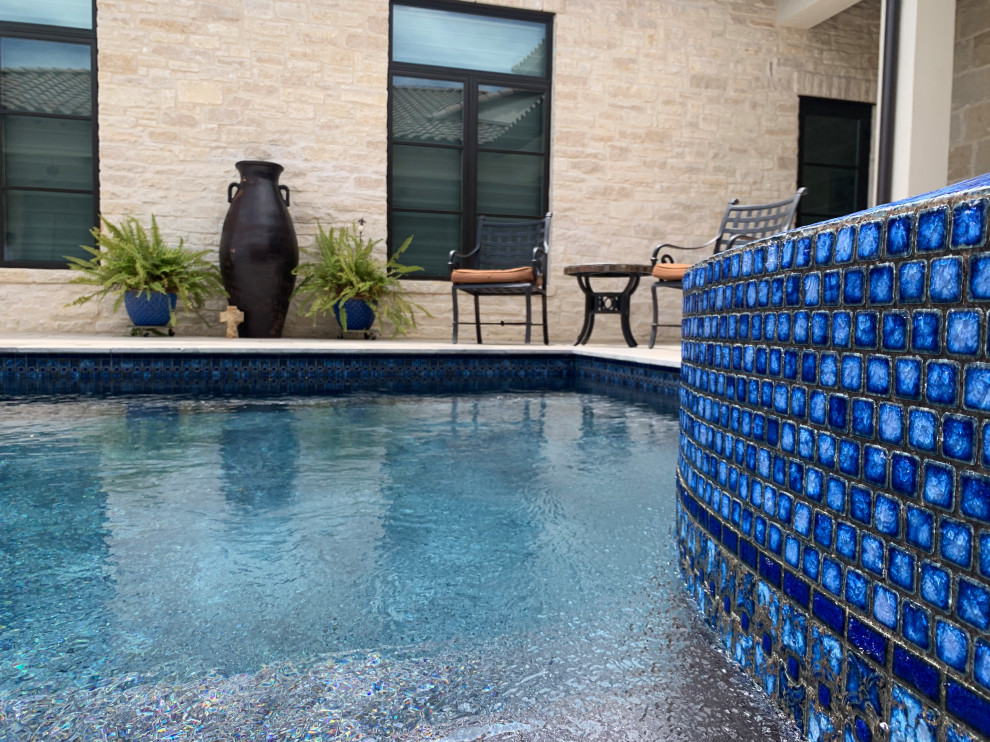 Photo of a large transitional courtyard rectangular infinity pool in Austin with natural stone pavers.