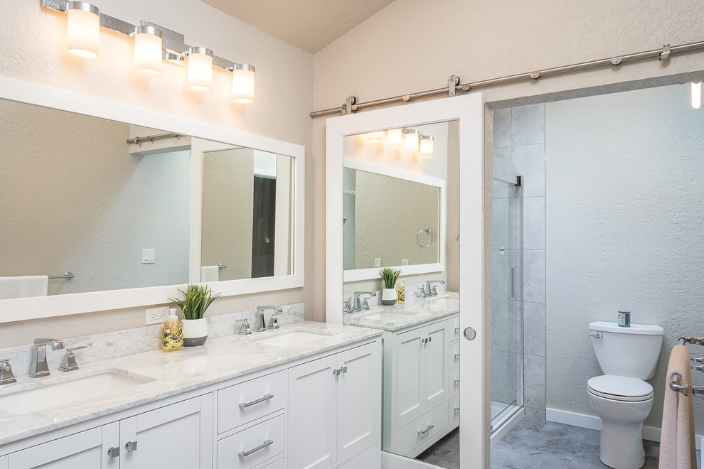 This is an example of a large contemporary kids bathroom in Seattle with shaker cabinets, an alcove tub, gray tile, porcelain tile, grey walls, porcelain floors, an undermount sink, marble benchtops, grey floor, white benchtops, white cabinets, an alcove shower, a two-piece toilet and a sliding shower screen.