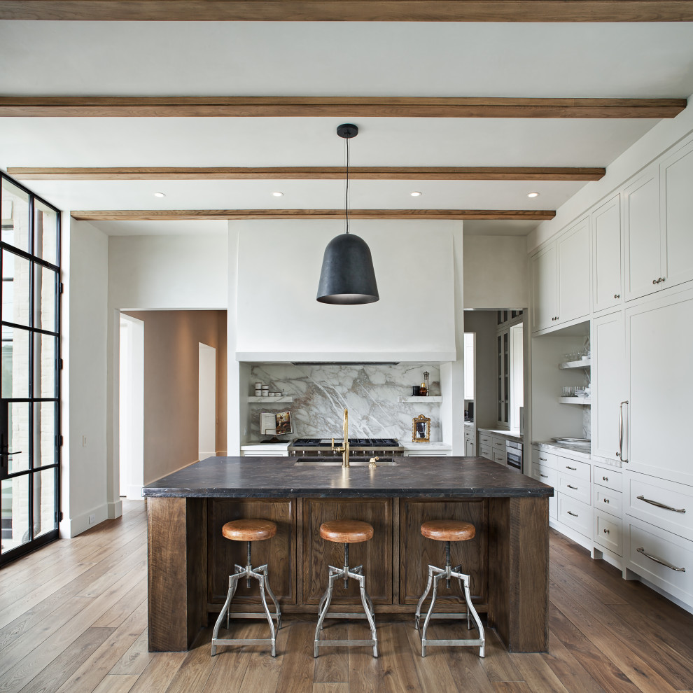 Inspiration for a large transitional u-shaped kitchen in Houston with an undermount sink, shaker cabinets, white cabinets, grey splashback, panelled appliances, with island, brown floor and black benchtop.