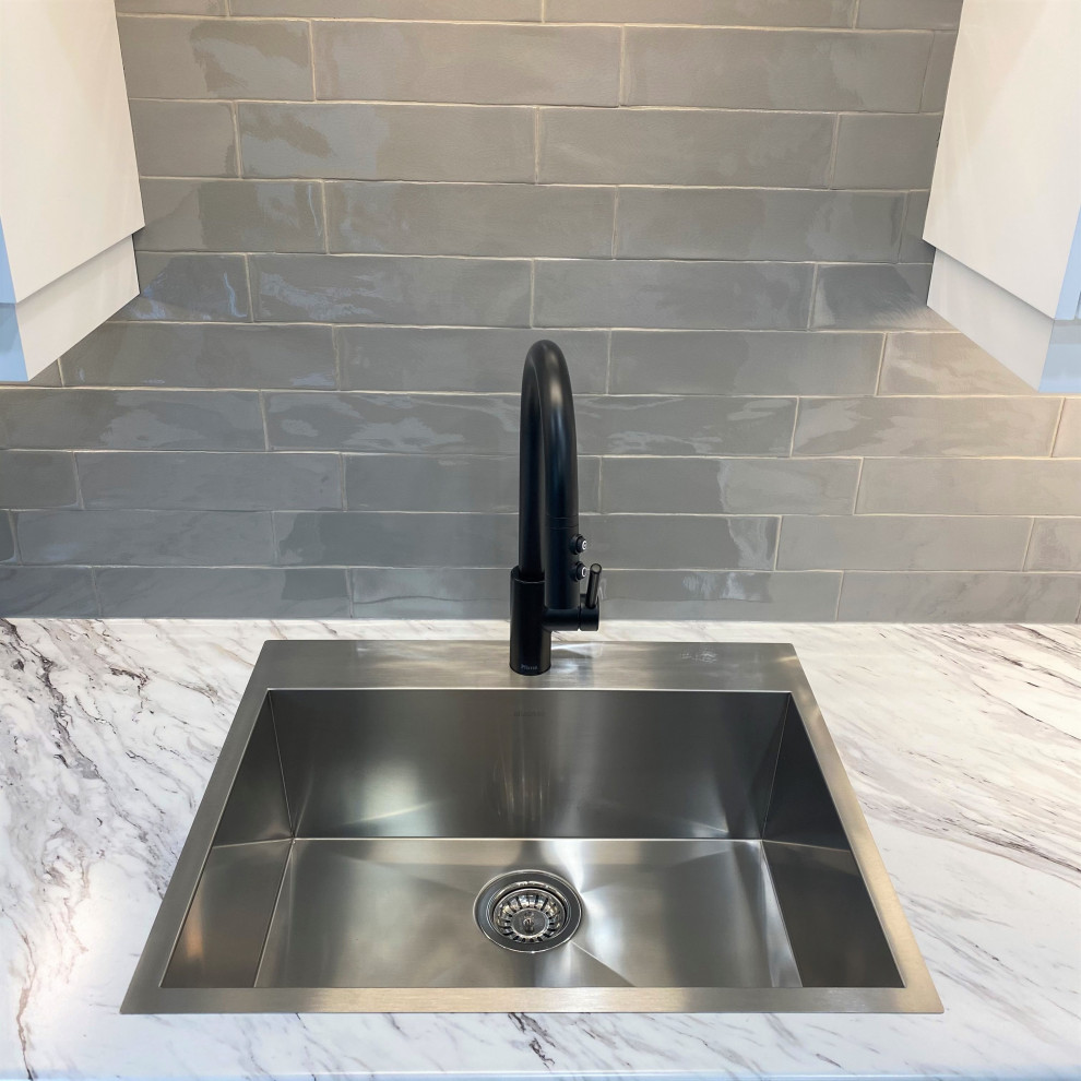 Eat-in kitchen - mid-sized transitional galley vinyl floor eat-in kitchen idea in Toronto with a drop-in sink, shaker cabinets, white cabinets, laminate countertops, gray backsplash and stainless steel appliances