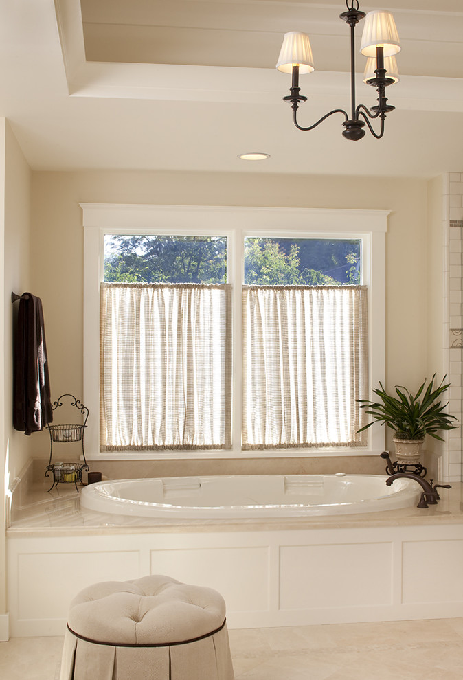 This is an example of a traditional bathroom in San Francisco with a drop-in tub and beige tile.