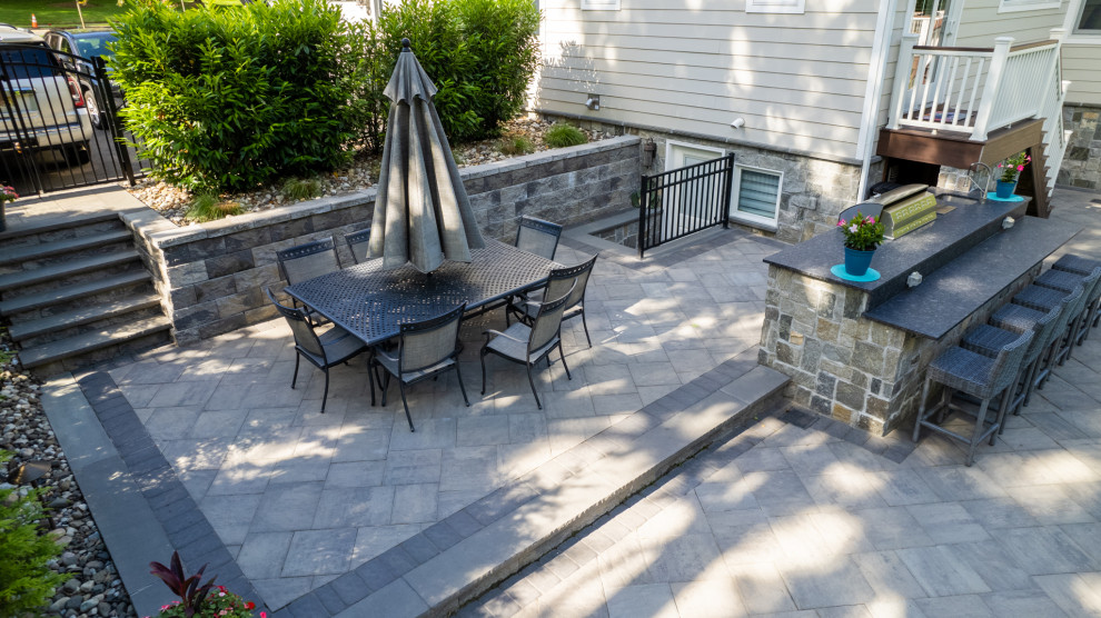 Photo of a large contemporary back patio in New York with an outdoor kitchen, concrete paving and no cover.