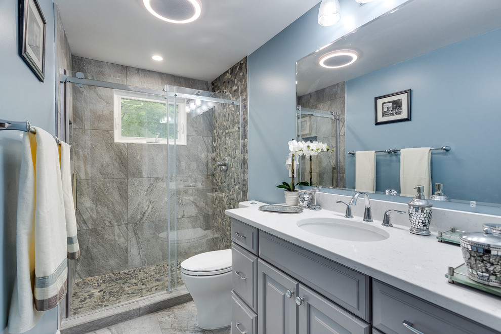 Mid-sized traditional master bathroom in DC Metro with raised-panel cabinets, grey cabinets, an alcove shower, a two-piece toilet, gray tile, stone tile, blue walls, ceramic floors, an undermount sink and laminate benchtops.