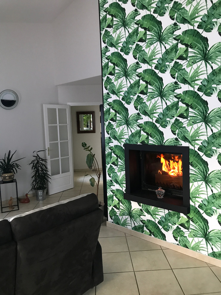This is an example of a mid-sized tropical open plan dining in Toulouse with green walls, ceramic floors, beige floor and a hanging fireplace.