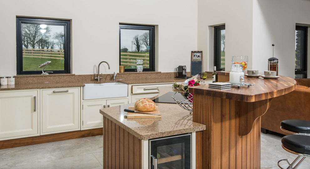 Photo of a large contemporary l-shaped open plan kitchen in Belfast with a farmhouse sink, beaded inset cabinets, white cabinets, granite benchtops, stainless steel appliances, porcelain floors, with island, white floor and multi-coloured benchtop.