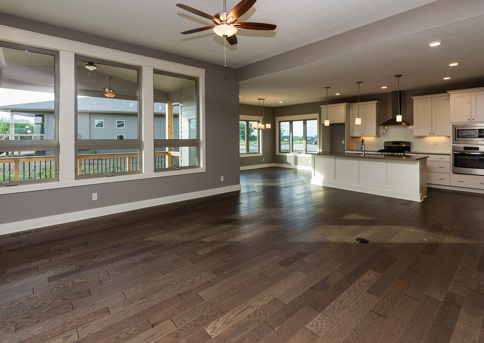 Transitional l-shaped dark wood floor open concept kitchen photo with an undermount sink, shaker cabinets, white cabinets, quartz countertops, white backsplash, subway tile backsplash, stainless steel appliances and an island
