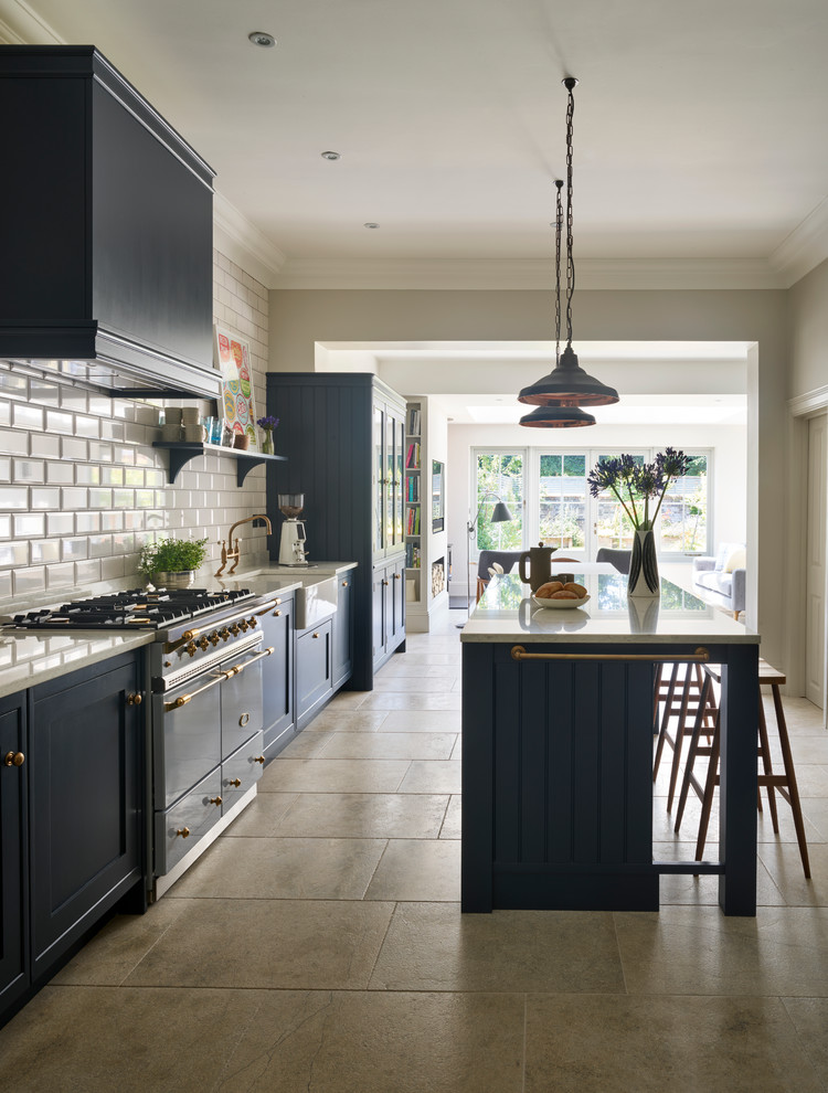 This is an example of a mid-sized transitional kitchen in Sussex with a farmhouse sink, white splashback, subway tile splashback, stainless steel appliances and with island.