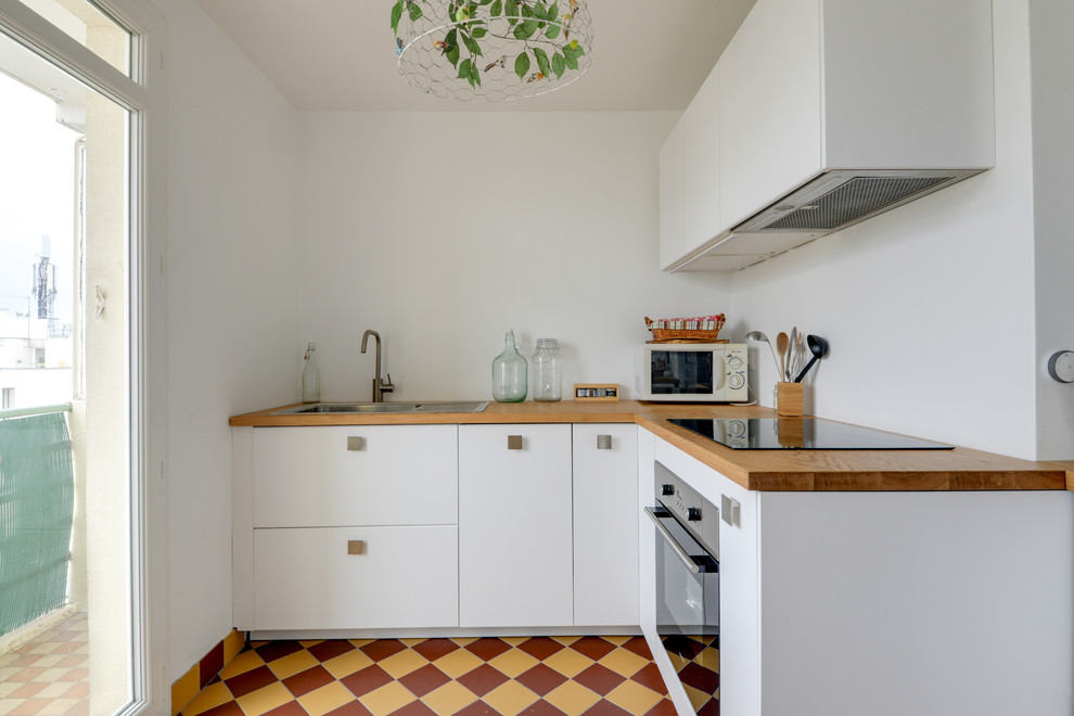 Photo of a mid-sized contemporary u-shaped eat-in kitchen in Paris with beaded inset cabinets, white cabinets, wood benchtops, ceramic floors, no island, brown benchtop, a single-bowl sink, stainless steel appliances and yellow floor.