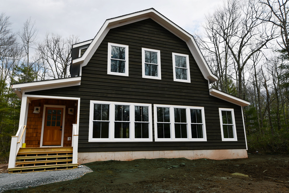 Large country two-storey grey house exterior in New York with wood siding, a gambrel roof and a shingle roof.