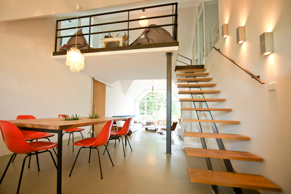Contemporary dining room in Munich with white walls and concrete floors.