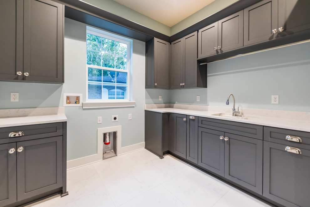 Inspiration for a large mediterranean l-shaped utility room in Jacksonville with an utility sink, shaker cabinets, grey cabinets, quartz benchtops, blue walls, porcelain floors, white floor, multi-coloured benchtop and a side-by-side washer and dryer.