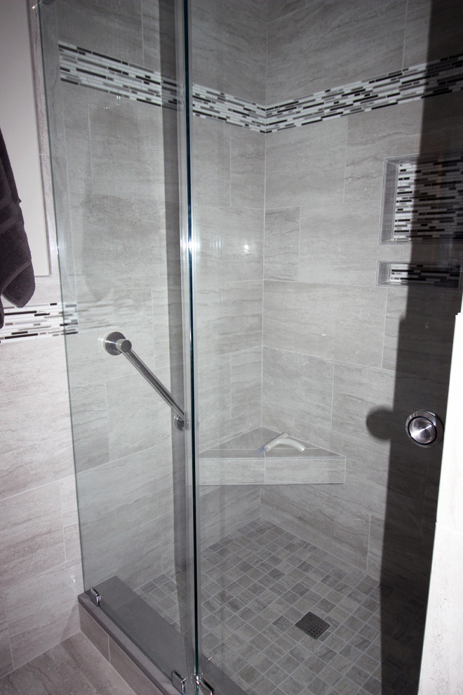 Photo of a large transitional master bathroom in Philadelphia with recessed-panel cabinets, dark wood cabinets, an alcove tub, an alcove shower, gray tile, porcelain tile, grey walls, porcelain floors, an undermount sink, engineered quartz benchtops, grey floor and a sliding shower screen.
