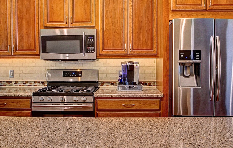 Eat-in kitchen - mid-sized l-shaped medium tone wood floor eat-in kitchen idea in Phoenix with a farmhouse sink, raised-panel cabinets, medium tone wood cabinets, beige backsplash, stone tile backsplash, stainless steel appliances and an island
