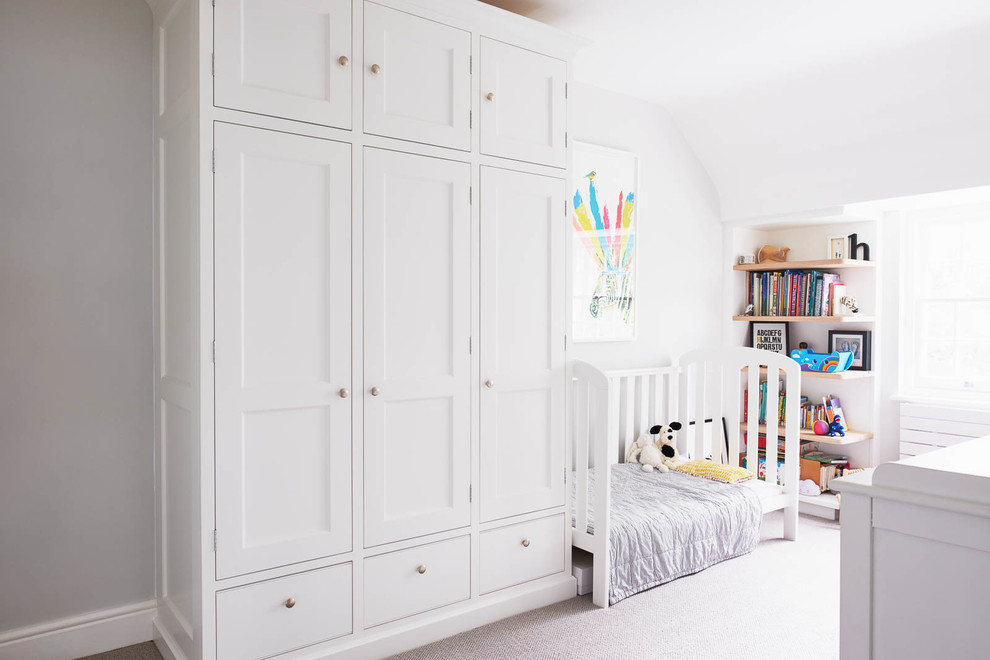 Photo of a mid-sized traditional toddler room for boys in London with white walls, carpet and grey floor.