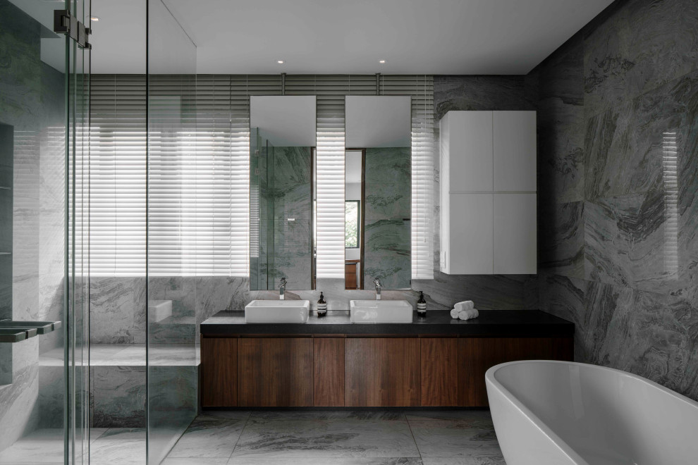 This is an example of a large contemporary master bathroom in Singapore with flat-panel cabinets, medium wood cabinets, a curbless shower, gray tile, a vessel sink, grey floor, a hinged shower door, black benchtops, a shower seat, a double vanity and a built-in vanity.